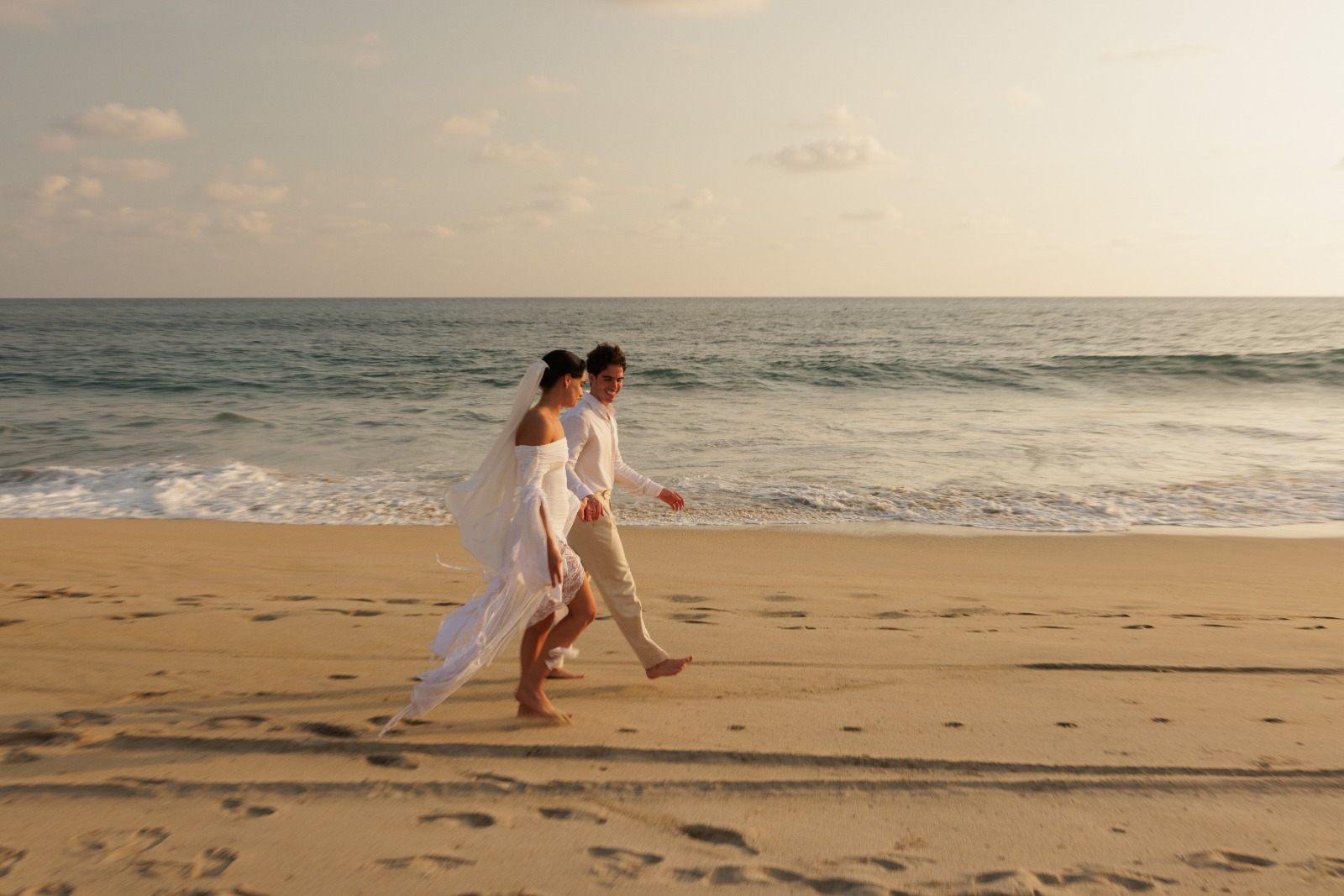Pareja caminando en la playa al atardecer en Puerto Escondido